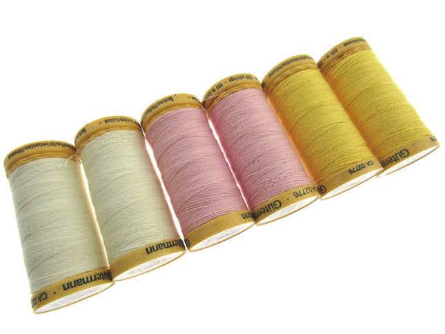 Set of six spools of thread in various colors on a white background