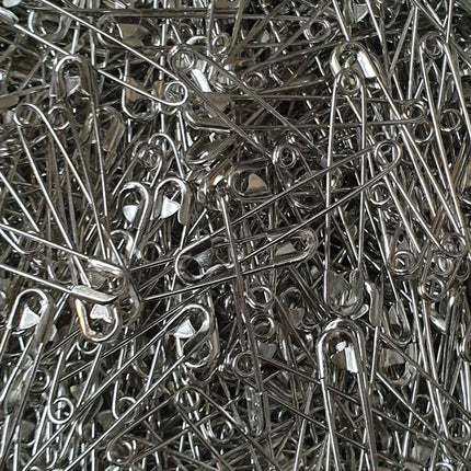 A close-up image of an assortment of nickel plated safety pins, showing their silver color and the looped end of the pins.