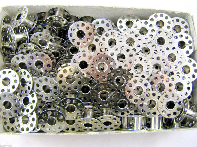 A collection of silver 15k sewing machine bobbins flat on both ends, with circular cut-outs in the centre.