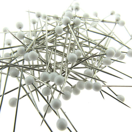 White glass head pins on a white background