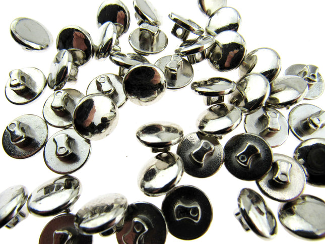 A collection of silver colored plastic mini buttons scattered on a surface.