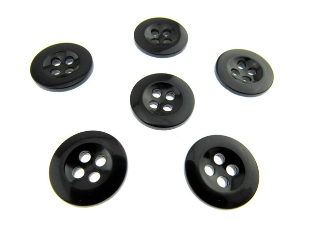 Six four hole black trouser buttons on a white background